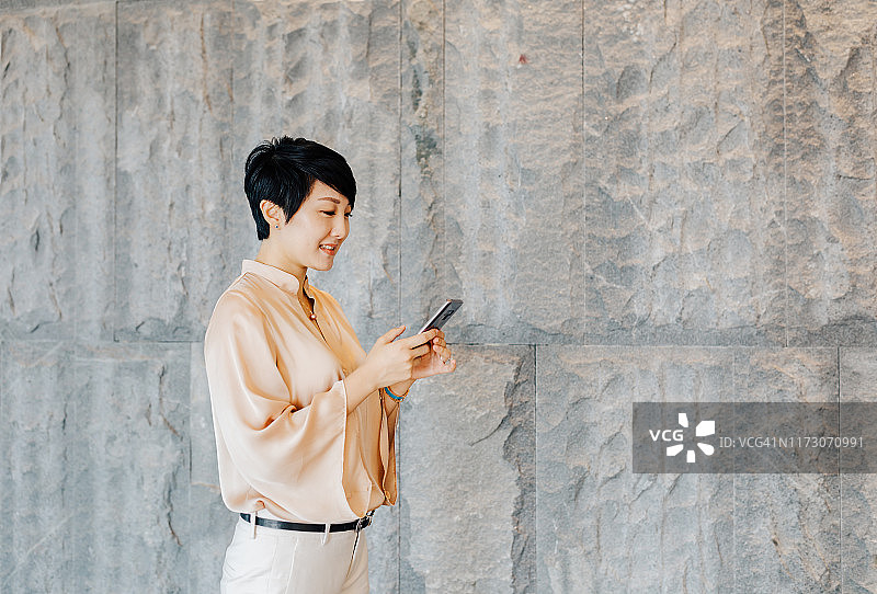 亚洲女商人在窗边使用手机图片素材