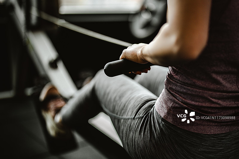 特写：在健身房划船机上锻炼的匿名女子图片素材