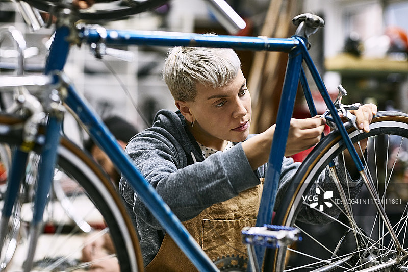 年轻女职员修理自行车刹车图片素材