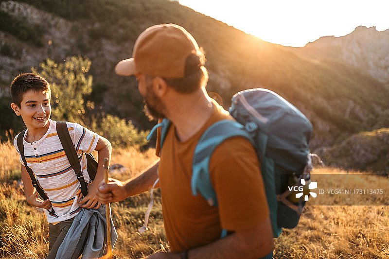 快乐的青少年男孩和父亲在山里图片素材