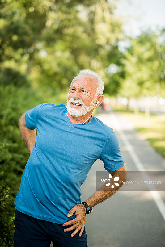 运动型老年男人在慢跑时背痛图片素材