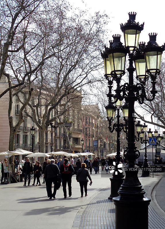 西班牙巴塞罗那历史中心著名的“兰布拉”绿树成荫的步行街上，秋季时节的精美锻铁路灯图片素材