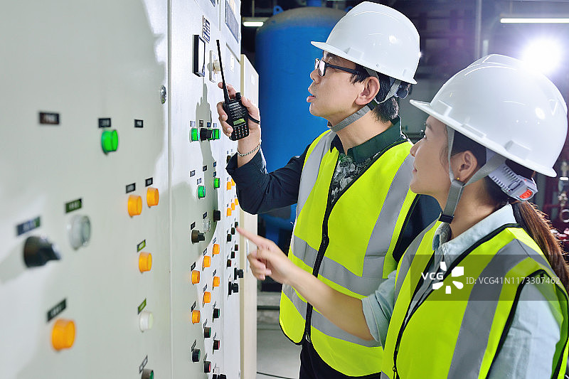 两名同事在电力控制面板前工作图片素材