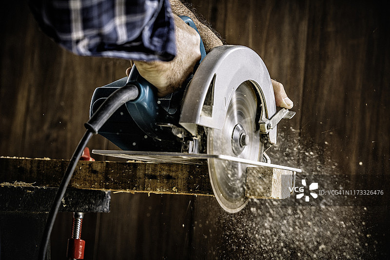 木匠在家用电动圆锯锯木头，木屑飞溅图片素材