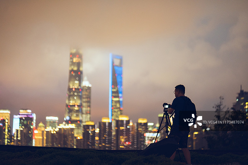 年轻男子在中国上海中央商务区使用相机图片素材