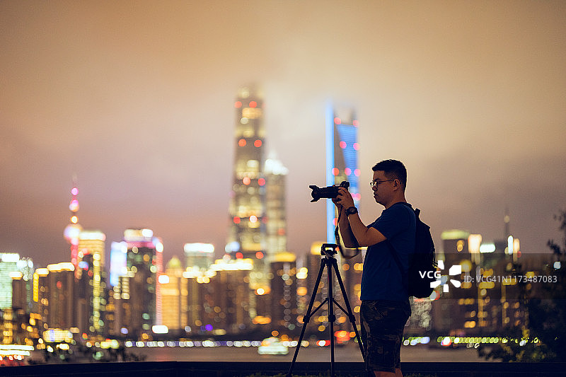 年轻男子在中国上海中央商务区使用相机图片素材