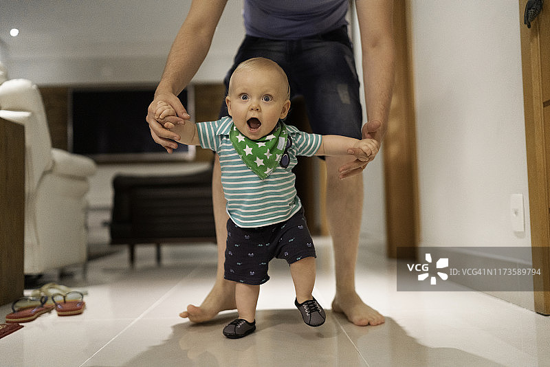 父亲在家帮助儿子学习走路图片素材