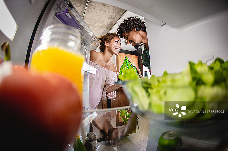 年轻女子和男人打开冰箱门图片素材