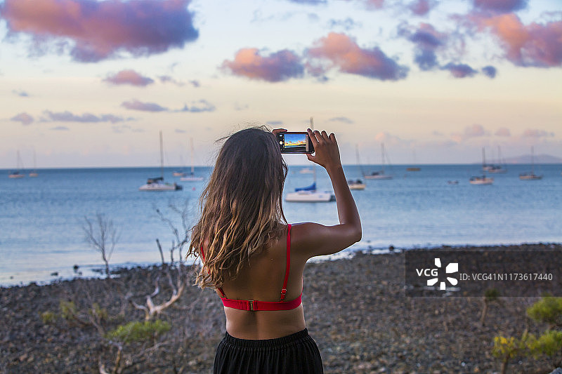 女孩在艾尔利海滩港口拍摄日落照片图片素材