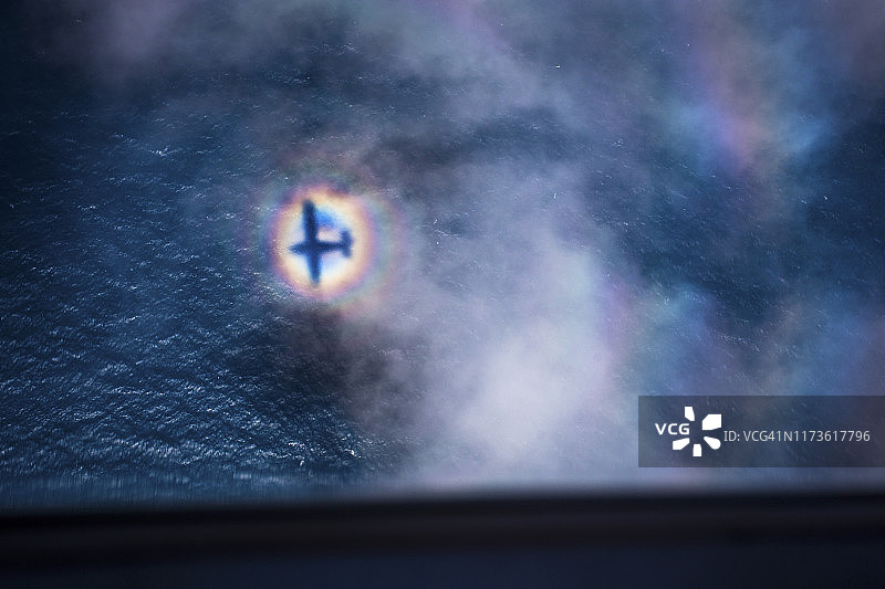 飞机穿梭云层，彩虹环绕图片素材