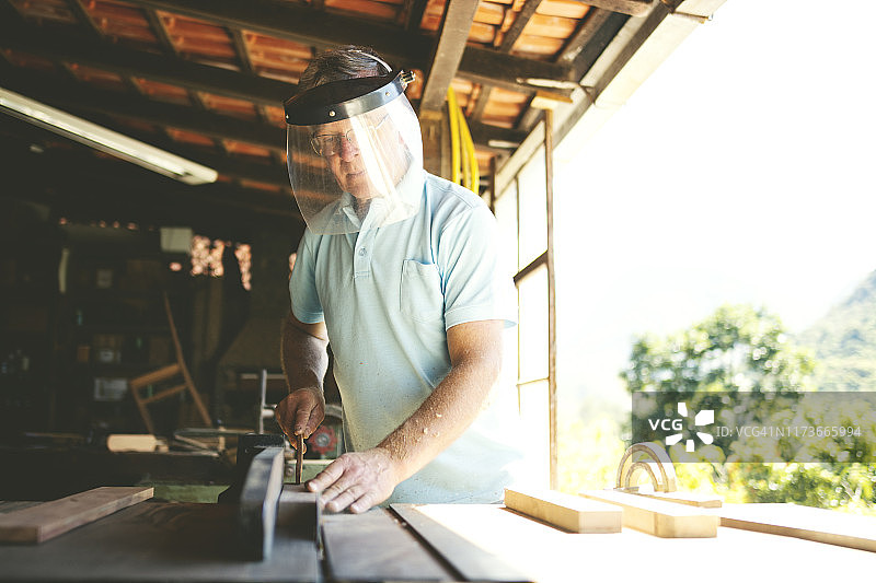 在木工作坊使用锯子的年长男人图片素材