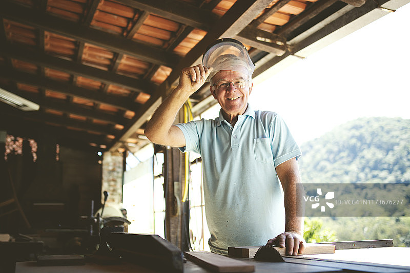 使用电动锯在木工车间工作的老年男人图片素材