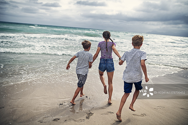 兄弟姐妹在海滩上奔跑图片素材