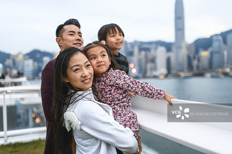 微笑的年轻中国家庭在香港享受黄昏图片素材