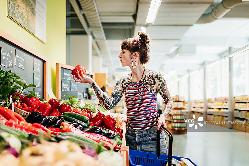 在超市看红辣椒的时尚年轻女性图片素材