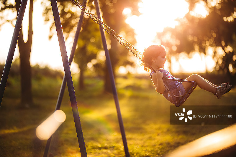 小女孩在日落时荡秋千图片素材