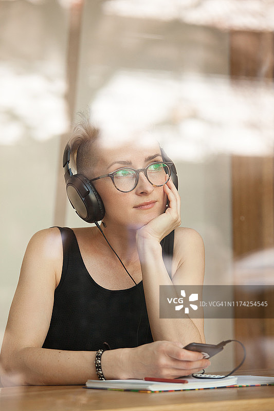 室内戴眼镜穿黑裙听音乐的30岁魅力女性图片素材