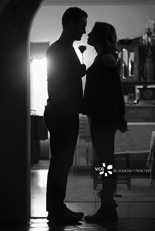 门口手持玫瑰的情侣剪影图片素材