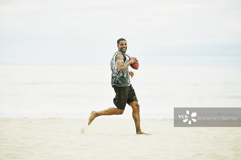 微笑男人在沙滩橄榄球比赛中达阵得分图片素材