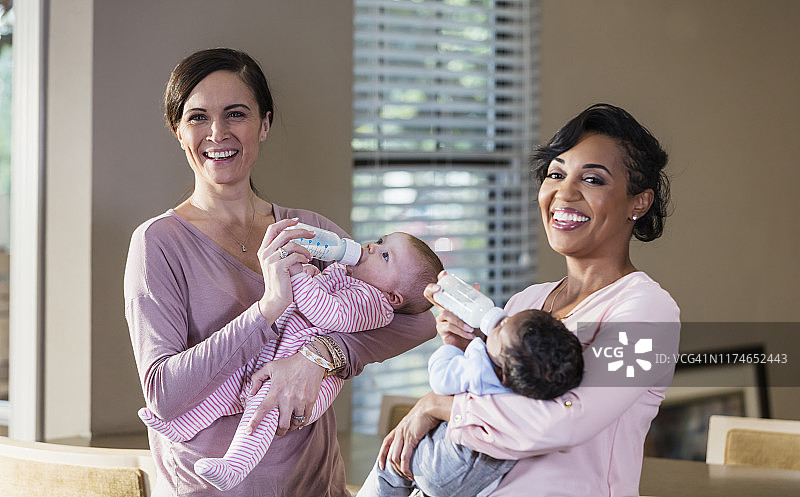 两位母亲用奶瓶喂养她们的宝宝图片素材