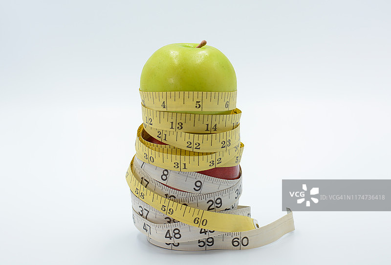 白色背景上用卷尺测量两个苹果的长度，饮食，健康生活方式图片素材