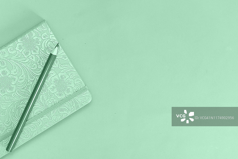 平铺白色办公桌面，黄色笔记本与绿叶图片素材