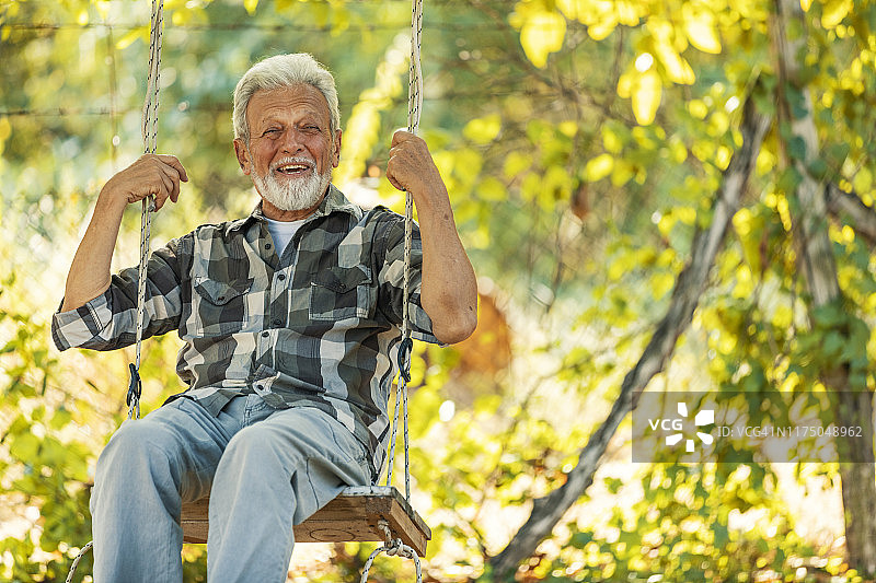 坐在秋千上的灰发年长男人肖像图片素材