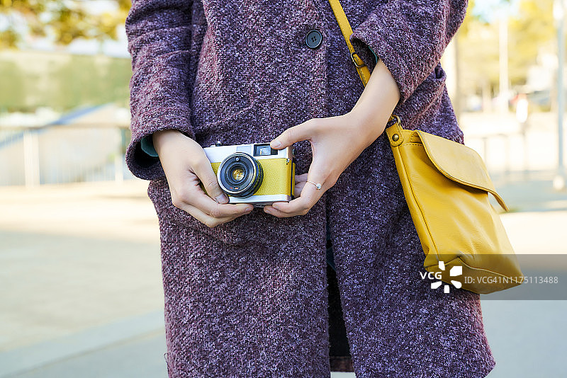 女人手持复古模拟相机特写图片素材