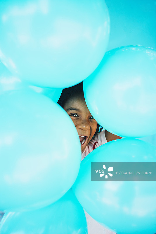 手拿气球站在蓝色墙壁前的小女孩图片素材