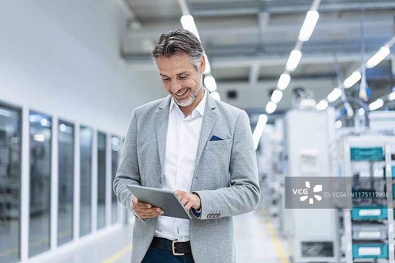 在现代化工厂使用平板电脑的微笑男士图片素材