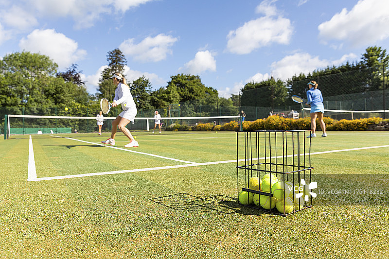 中年妇女在草地球场上打网球图片素材