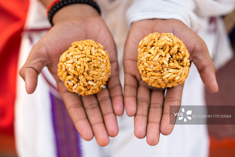 在印度瓦拉纳西克达尔 घाट的恒河岸边，一位室利·维迪亚·玛特 शिष्य（弟子或学生）手持米糕图片素材