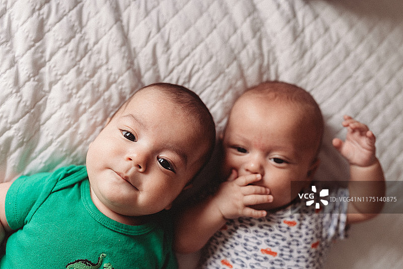 三个月大的异卵双胞胎在白色床上玩耍图片素材