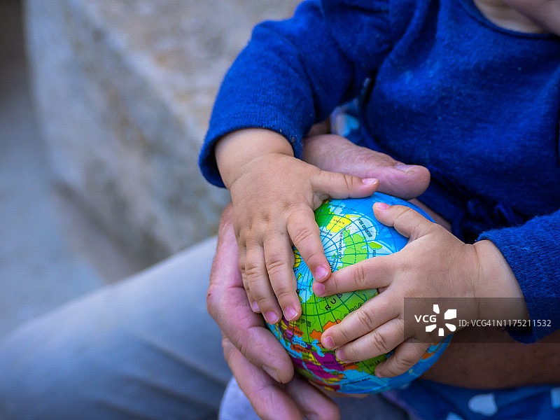 祖父和婴儿的手拿着地球仪：生态与全球化概念图片素材