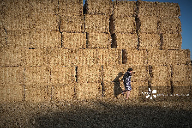走过法国新阿基坦德塞夫勒省田地里一堆干草捆的女人图片素材