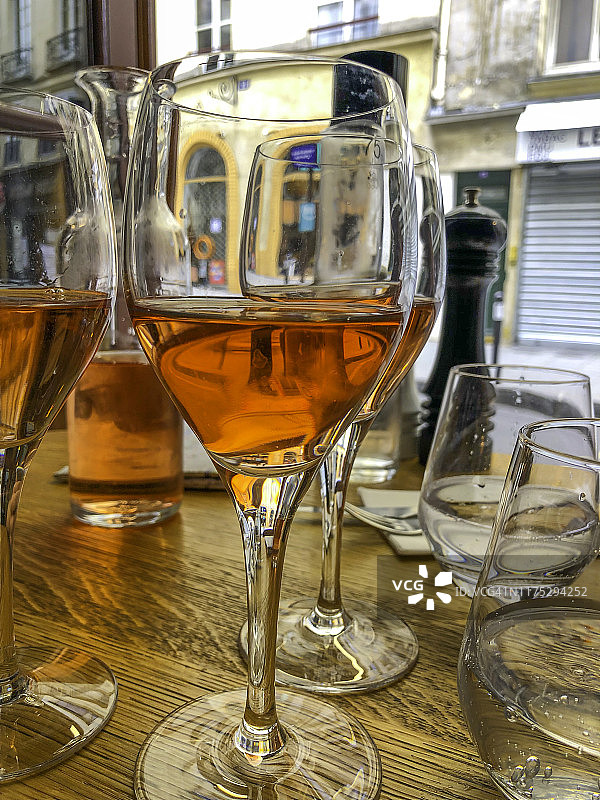 几杯桃红葡萄酒，木桌上放着水杯和胡椒研磨器图片素材