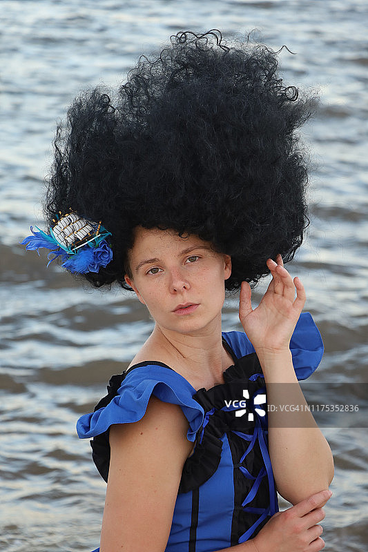 海滩上身穿蓝色和黑色连衣裙的黑发美女特写图片素材
