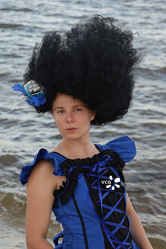 海滩上身穿蓝色和黑色连衣裙的黑发美女特写图片素材