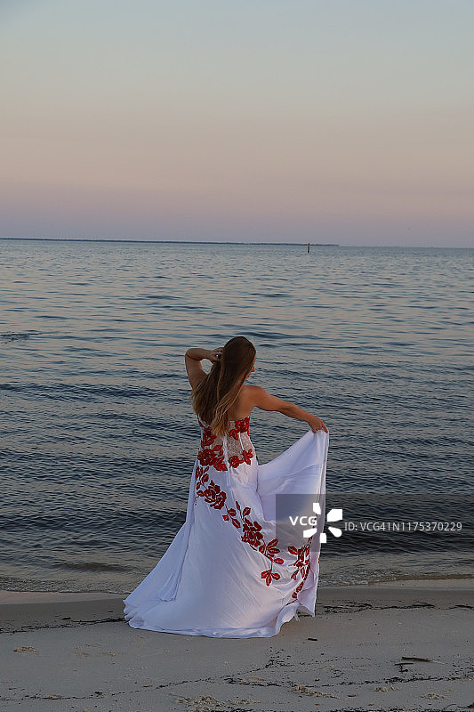 女士身穿白色长裙站在海滩上图片素材