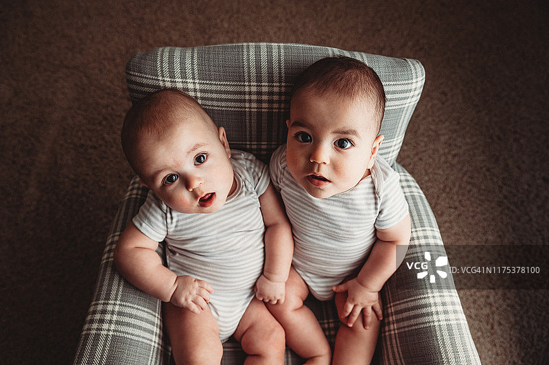7个月大的男异卵双胞胎坐在格子摇椅上图片素材