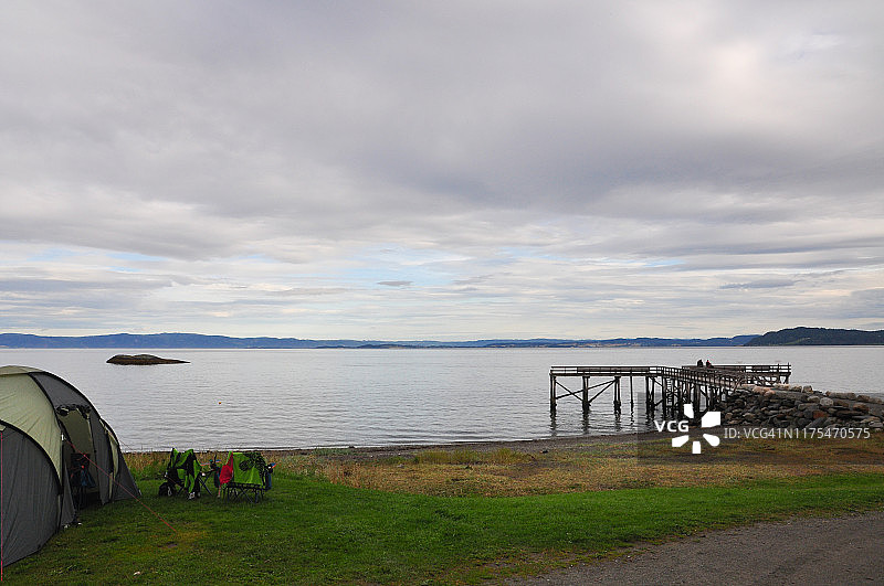 挪威夏末假日：海边露营地的帐篷和旧木码头图片素材
