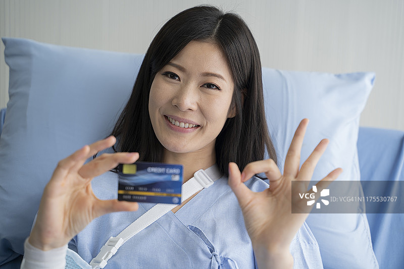 年轻亚裔女患者出示信用卡并做出OK手势图片素材
