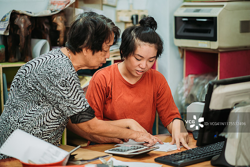 中国女性帮助祖母在水果店整理账目图片素材