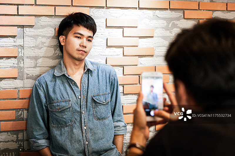 两名年轻的亚洲男子和他的朋友们用智能手机拍照图片素材