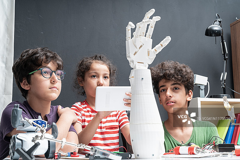 三个学童试图组装一个机械臂图片素材
