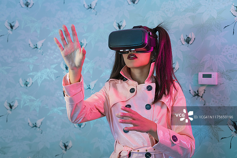 佩戴VR眼镜的年轻女子挥动手臂图片素材