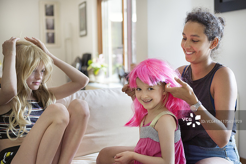 青年与两个孩子试戴彩色假发图片素材