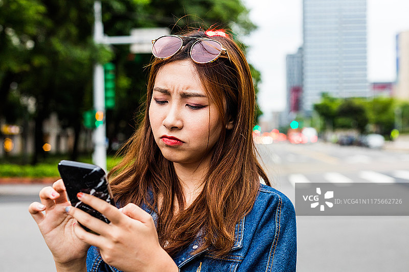 在街上使用智能手机的沮丧女子图片素材