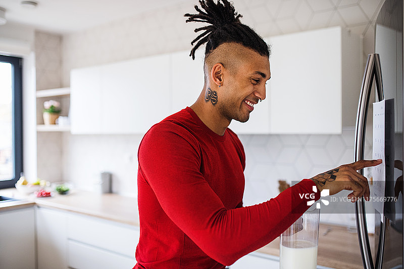 在家锻炼后从冰箱里拿牛奶的健壮混血男人像照片图片素材
