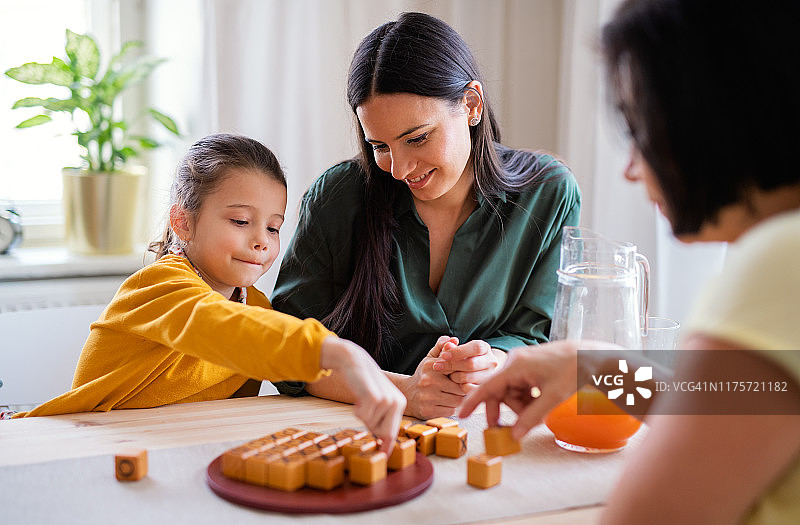 祖母、母亲和孙女坐在家里的桌旁玩棋盘游戏图片素材